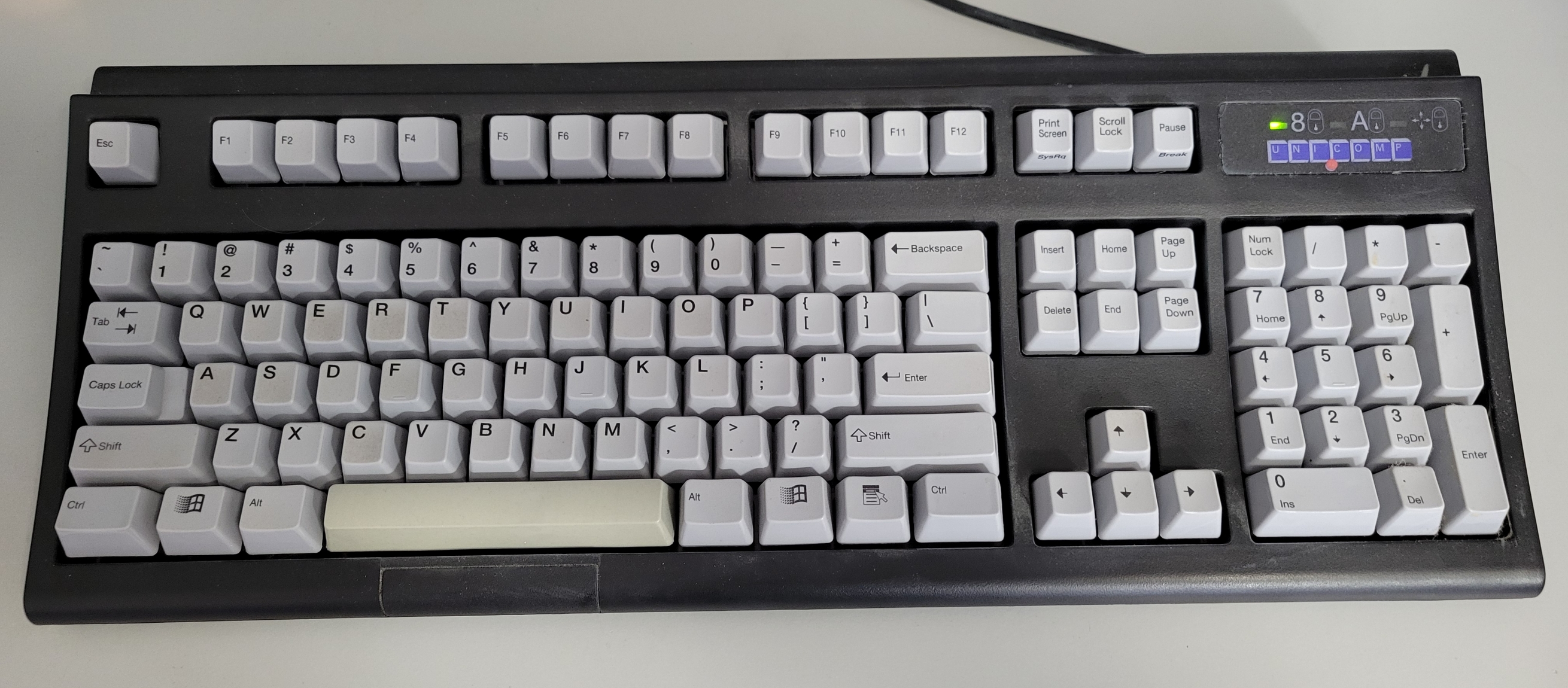 A Unicomp mechanical keybaord with white keys on a black frame.