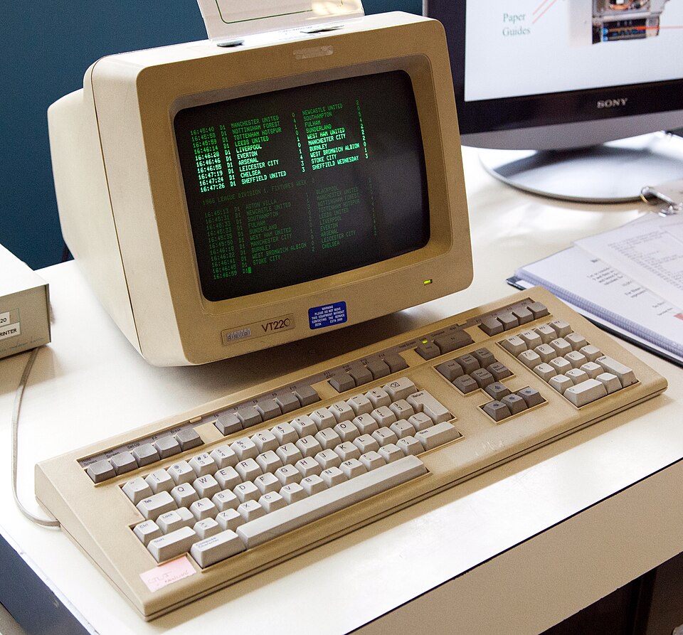 a VT220 terminal showing a file listing in plain green text; a keyboard is in front of the terminal