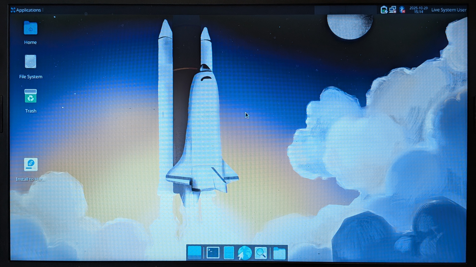 Fedora Xfce desktop with icons on the desktop, menu bar at top, and program icons at bottom. The desktop wallpaper is the NASA shuttle launching into space.