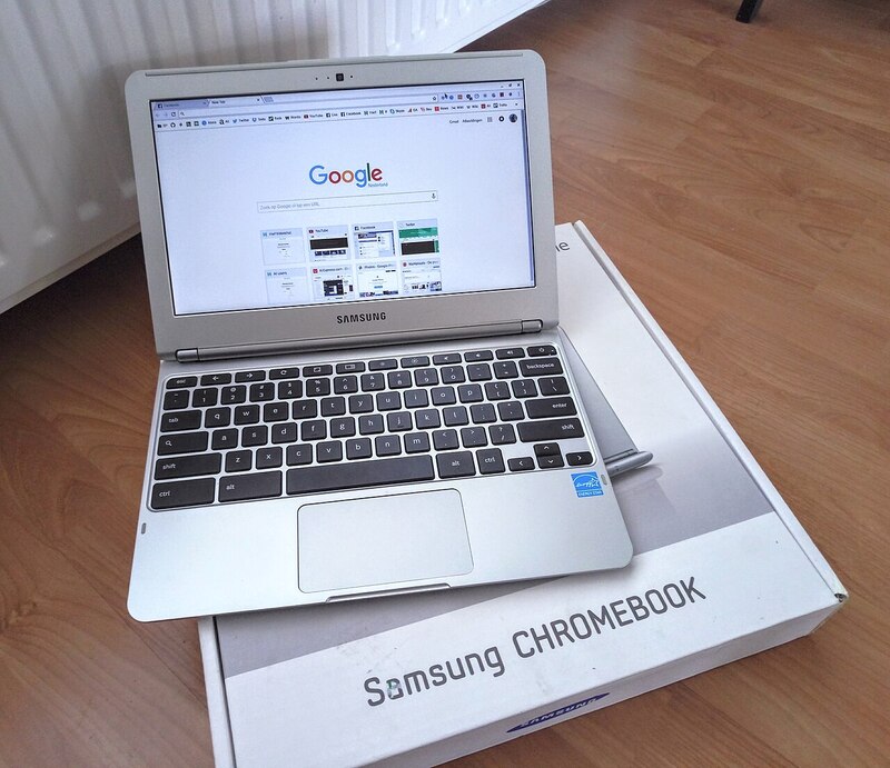 A gray Samsung Chromebook laptop, the screen shows the Chrome web browser open to the Google home page.