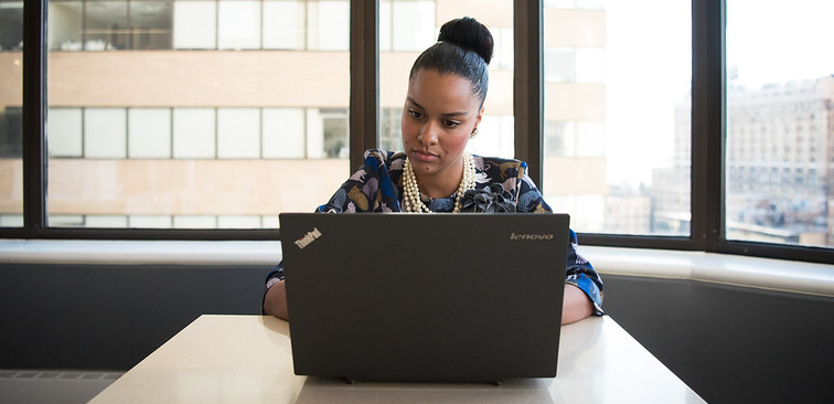 A Black femail working on a computer in an office.